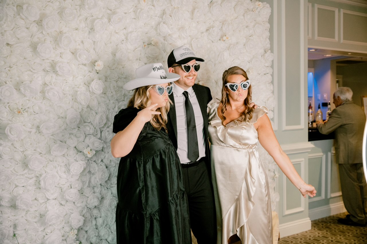 Guests using Photo Booth with White Rose Flower Wall